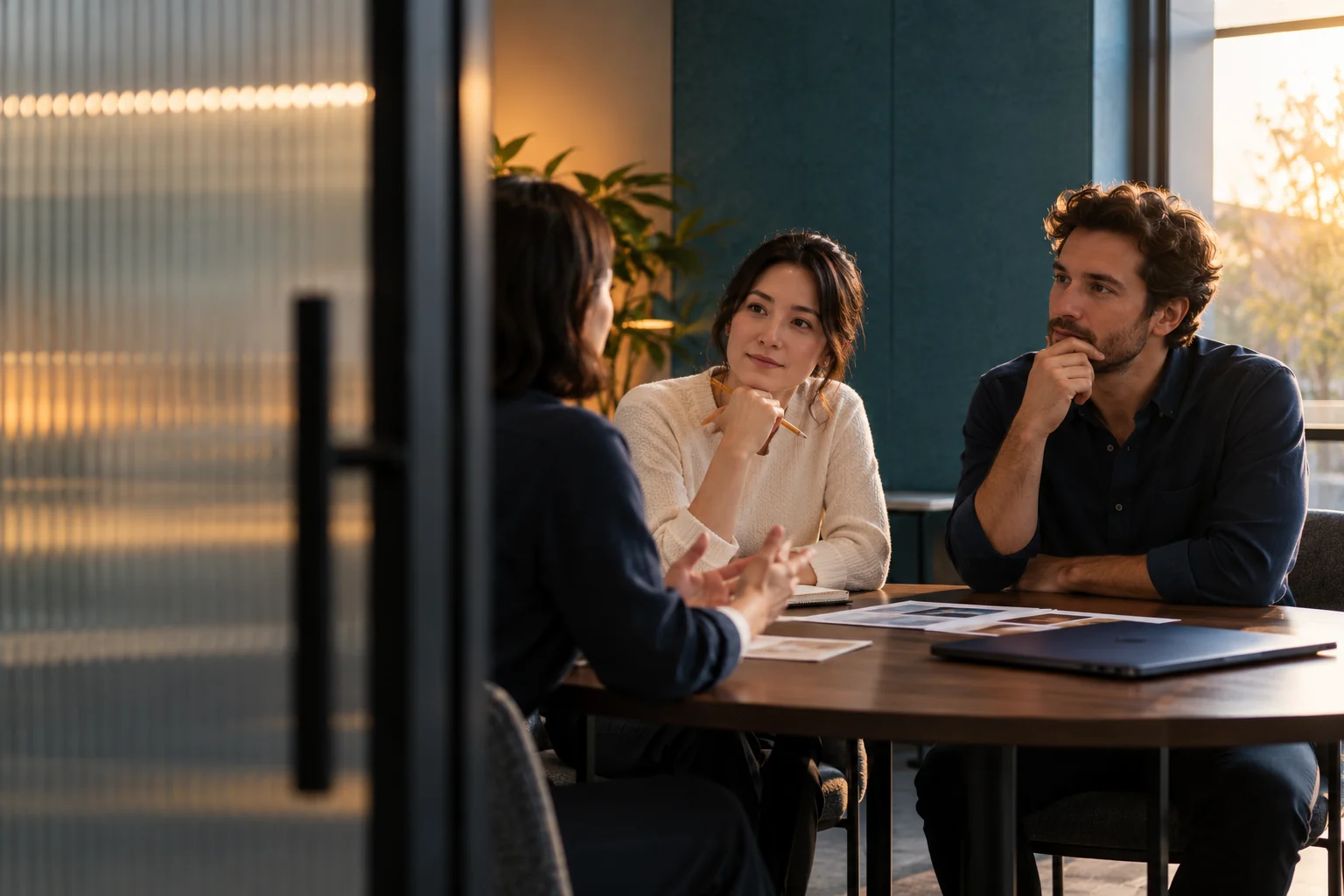 Conceptual professional discussion with two participants listening in a sunlit meeting room